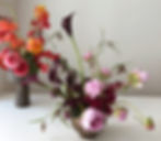 2 bouquets de fleurs dans un vase, posés sur une table