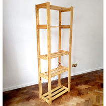 Free standing wooden shelving unit on wooden flooring against a white wall