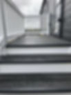 Steps to lodge decking made out of PVC with white balustrade and grey decking boards with a small platform area covering one door of the lodge