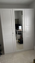 Triple white wardrobe in bedroom with a glass door in the middle and two plain white door on each side