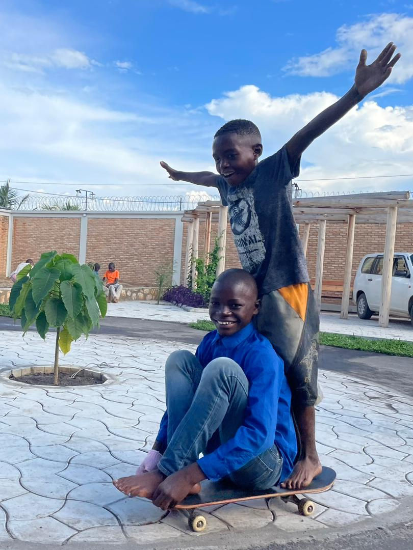Two boys in Burundi on a skateboard.