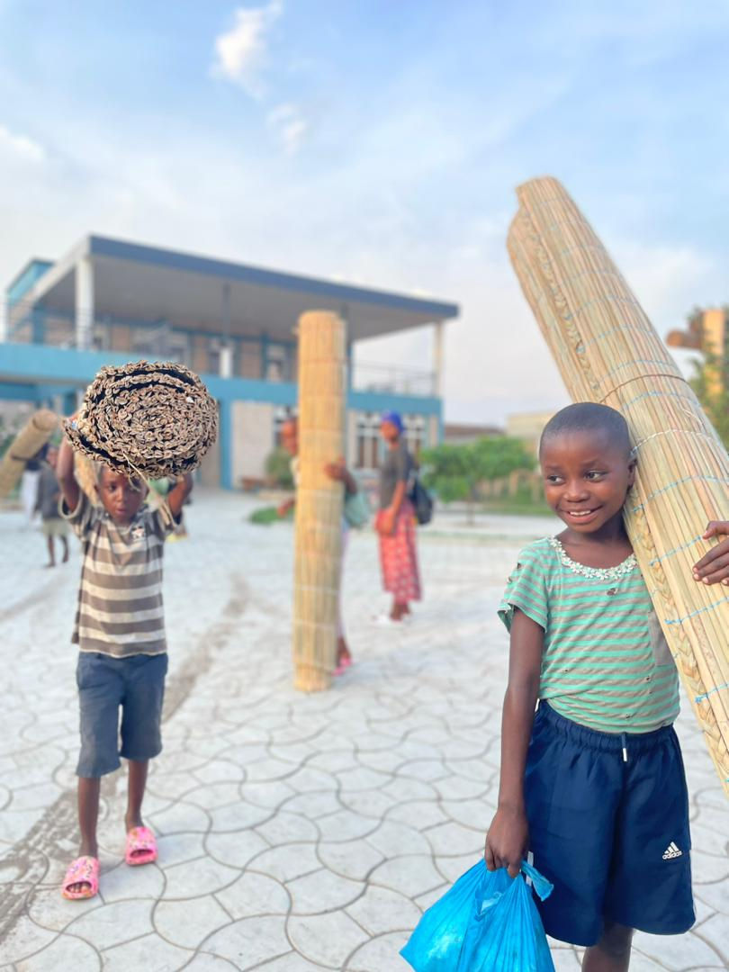 Children carrying mosquito nets and sleeping mats