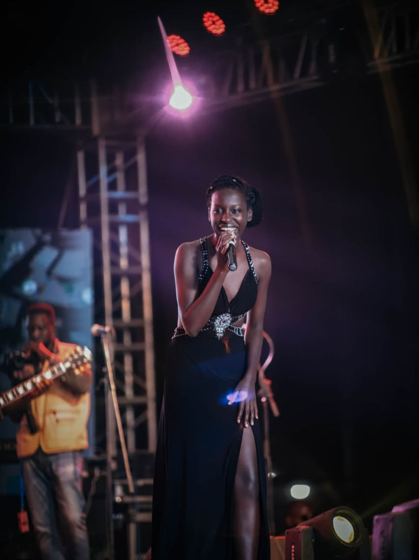 A woman on a stage with lights on singing