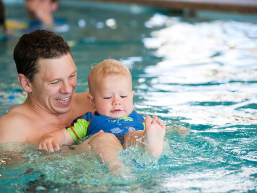 a dad enjoying swimming lessons with his toddler at AquaBuddies