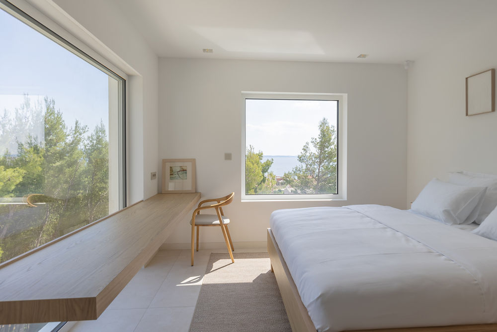 Bedroom in Villa C with large windows, desk, and sea view