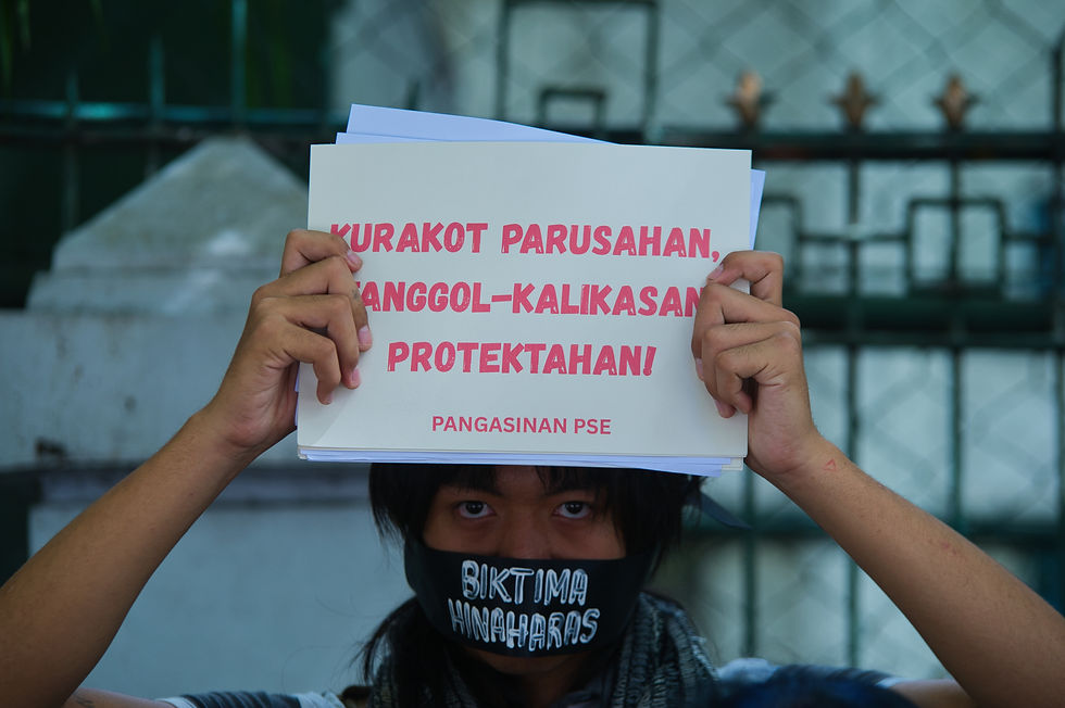 A protester muzzled by a black ribbon baring the words "biktima hinaharas" carries a placard calling for sanctions against corruption officials and protection for environmentalists