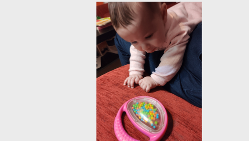 תינוקת נשענת על כפות ידיים בשכיבה על ברכי מבוגרת  