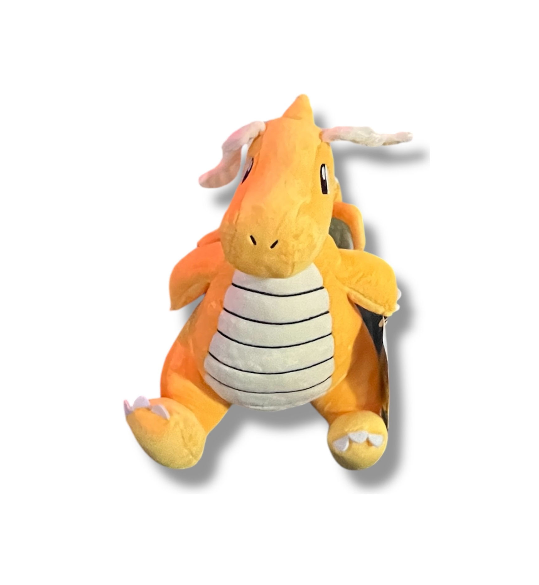 Dragonite stuffed plush toy, orange and yellow, on a white background.