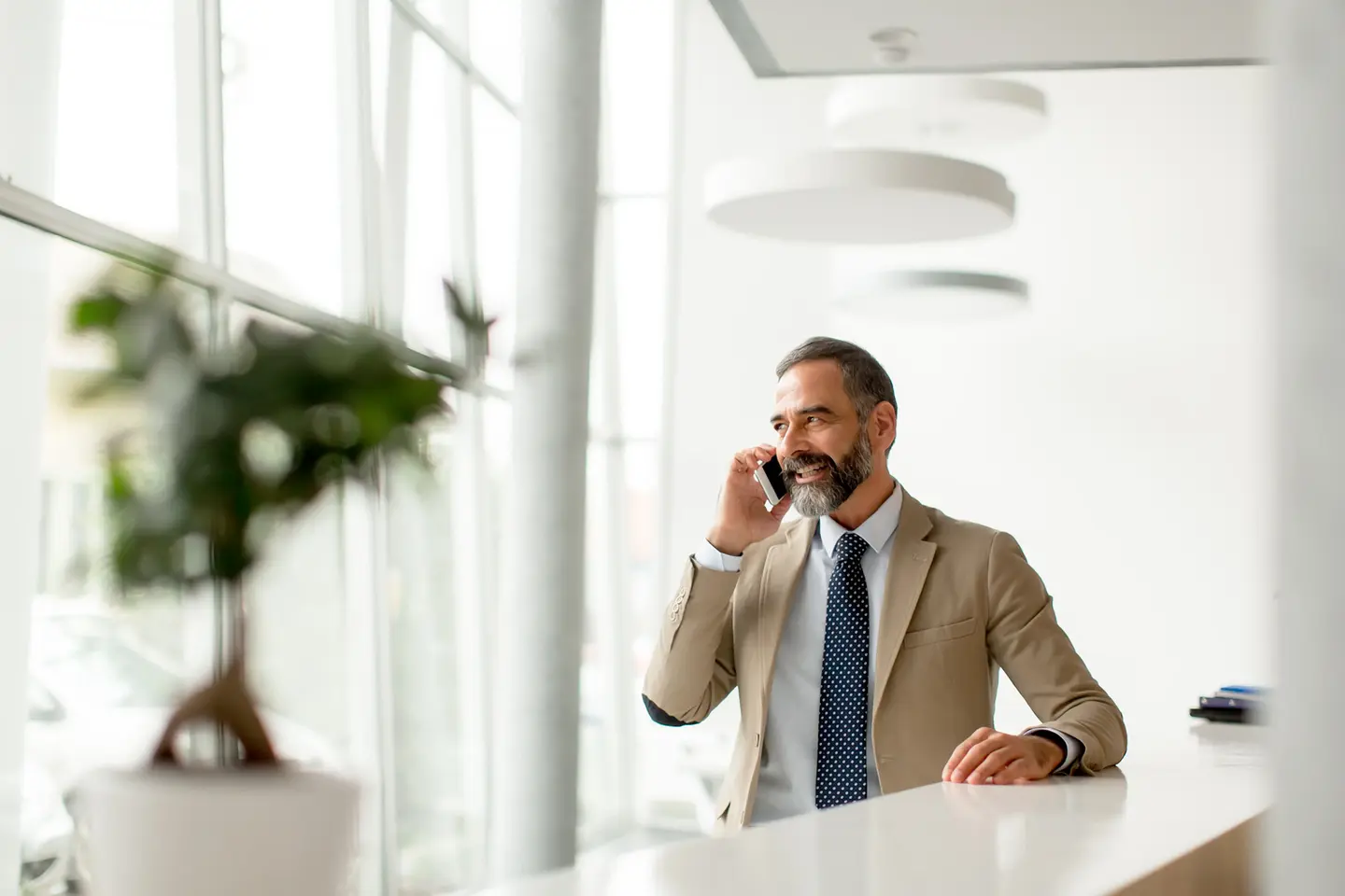 Smiling businessman on phone call, office setting
