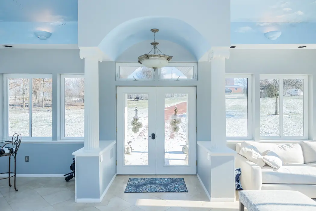 Sunroom with French doors, light blue walls, and view of snowy landscape