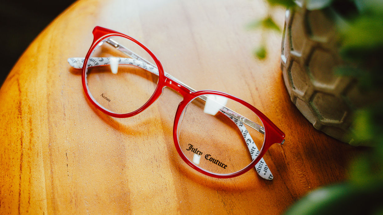 Red Juice Couture eyeglasses on wood table