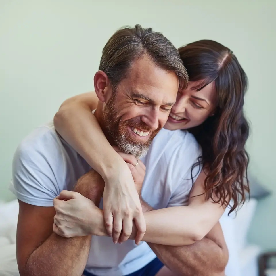 Happy couple embracing playfully in bedroom