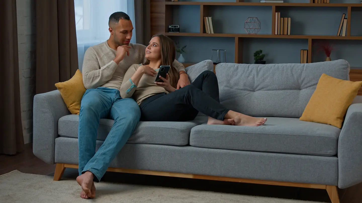 Couple relaxing on couch, looking at phone