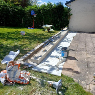 Chantier maçonnerie maçon malaxeur mortier et drainage gravier muret jardin.