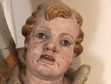 A statue of cherub looking onwards with little life behind its eyes