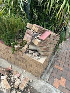Heavily damaged red brick letterbox showing cracks and structural issues, before restoration