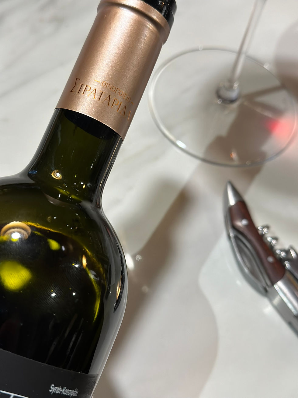 cuello de botella en fondo blanco con un descorchador y copa de vino