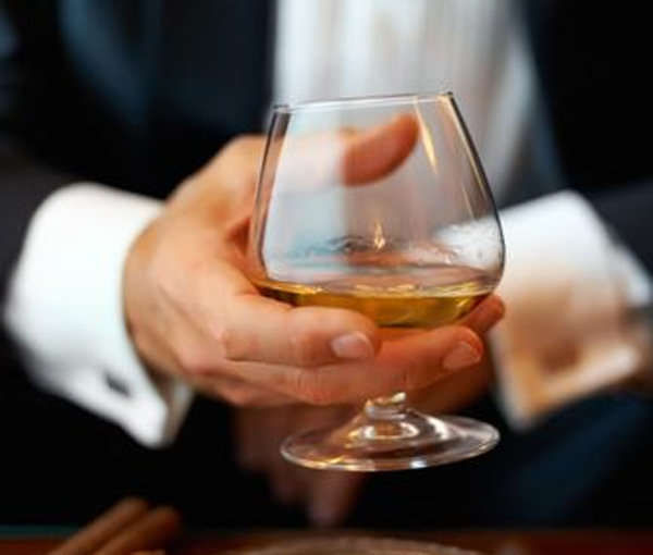 Hombre sujeta una copa coñaquera con cognac