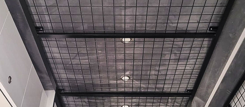 Overhead storage system within the rear workshop, featuring a robust metal grid structure running along the ceiling. The elevated design makes intelligent use of otherwise unused space, helping keep equipment securely stored while maintaining valuable working room below.
