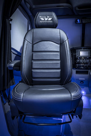 Close-up view of the driver’s seat in black leather with the "Sporthomes" logo on the headrest. The stylish stitching emphasizes its premium quality.