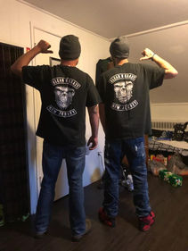 2 Members wearing MC shirts and pointing to logo on back