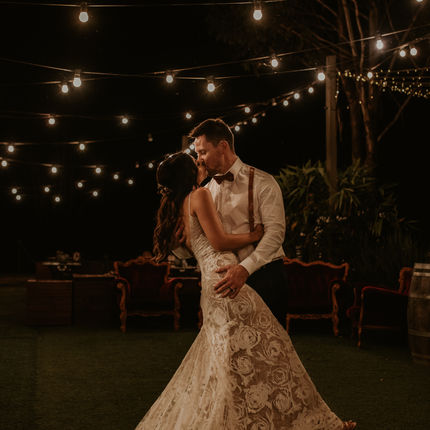 Bride and groom first dance under festoon lights. 