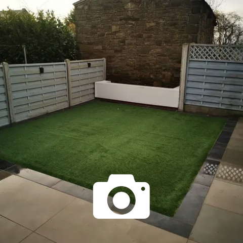 Honed Indian stone, artificial grass, rendered wall. Tarmac drive with block edging