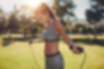 A woman outside in the sun skipping as part of a weight loss workout. She is jumping rope because it is an excellent form of physical fitness. As well as burning fat, getting the heart rate up and skipping also improves whole-body fitness.