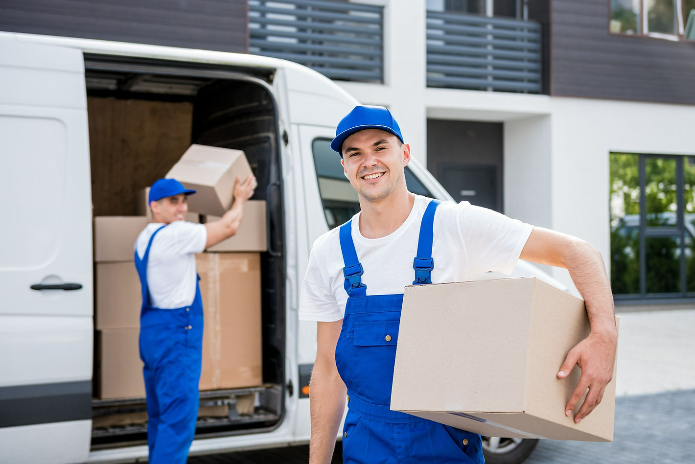 two-removal-company-workers-unloading-boxes-from-minibus-into-new-home.jpg