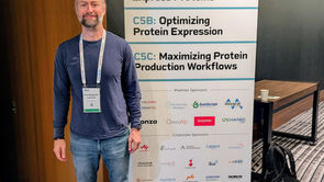 Photo of Chris Lennon standing in front of a white and blue protein sign.