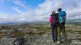 Zwei Wanderer stehen und betrachten die Landschaft am Horizont. Norcota Team