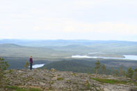 Person betrachtet die grüne Landschaft mit Seen unter dem bewölkten Himmel.