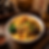 Bowl of noodles topped with greens, mushrooms, minced meat and scallions on a wooden table with chopsticks and a Chinese menu sign.