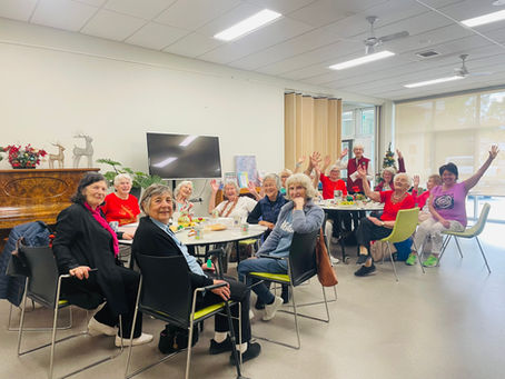 Group of older women sitting at tables chatting and smiling