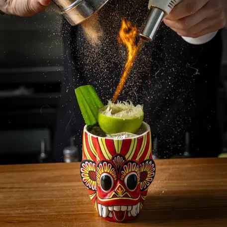 Mask on fire cocktail with plantation pineapple, ginger, whey, pandan finished with a cinnamon fire show by Mindset Spirits