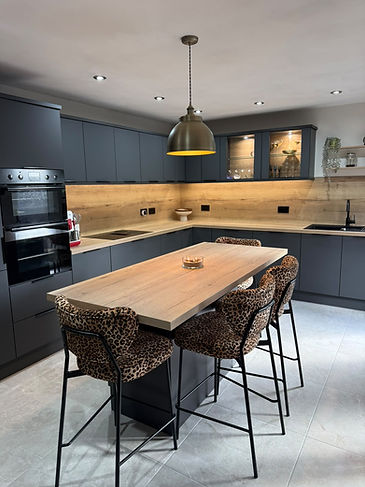 Modern dark grey kitchen featuring wood top island with leopard print bar stools
