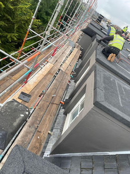 Workers installing flat roofing on a building with scaffolding