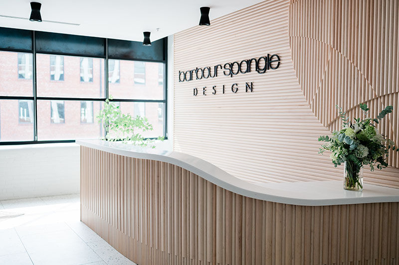 Interior design firm lobby design with channeled wood wall and curved desk