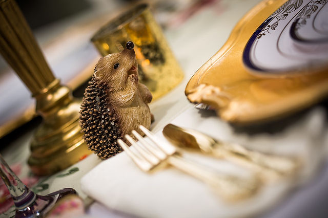 Whimsical porcupine garden statue displayed among lush greenery, colorful flowers, and vintage-inspired garden party décor.