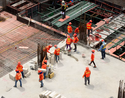 Group of construction workers are seen standing on an under construction building