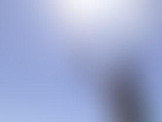 Man in tank top and hat uses fishing rod to control drone under clear blue sky. Sunlight creates a bright and relaxed atmosphere.