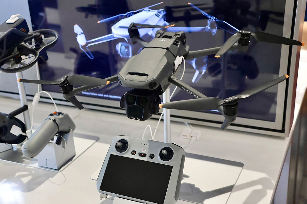 Gray drone on display with a remote controller, featuring "MAVIC 3 PRO" text. Background shows a screen with a similar drone image.