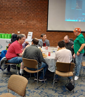 People On the Go members, with intellectual and/or developmental disabilities, sitting around a conference table in the September 2022 Quarterly Meeting. 