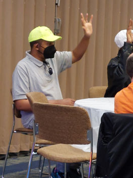 A People On the Go member raises hand in participation while sitting at a conference table in the September 2022 Quarterly Meeting. 