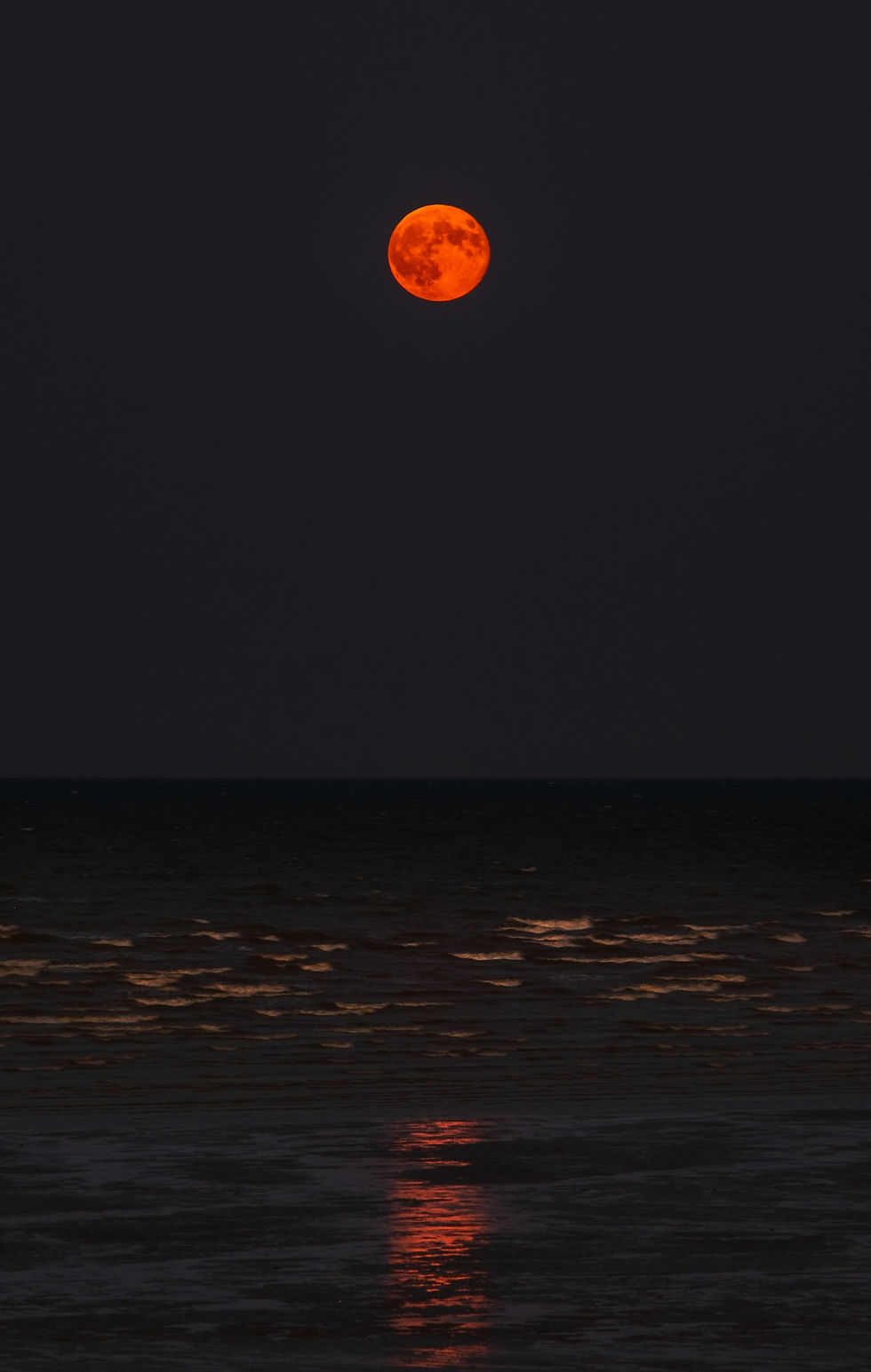 Eclipsed moon over ocean