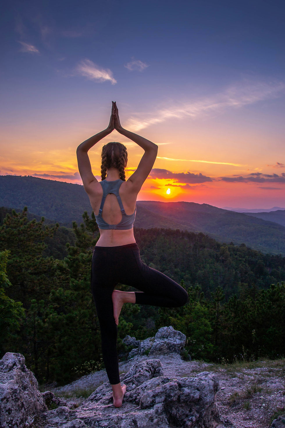 Woman balancing in a yoga pose facing the setting Aries Sun