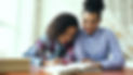 Adult helping a child with reading or homework at a table