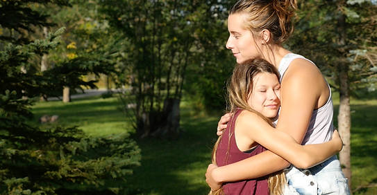 Adult and child hugging outdoors in a caring and supportive moment