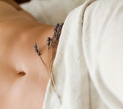 Getrockneter Lavendel auf einem nur zum Teil mit Handtuch bedeckten Bauch.