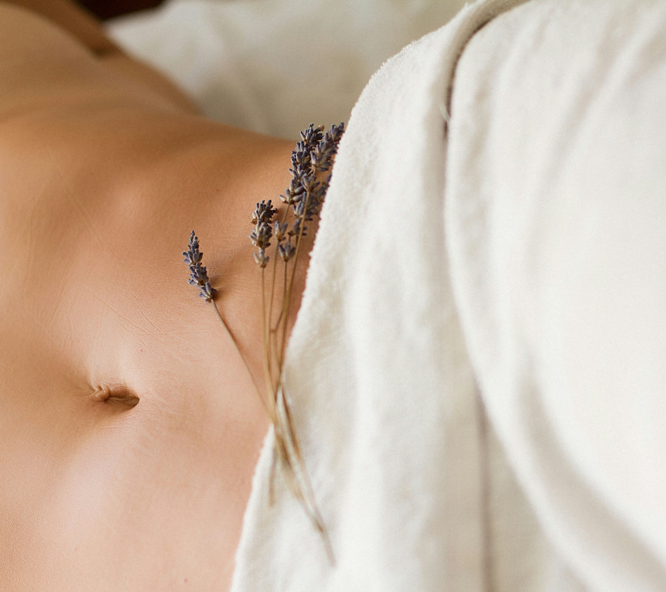 Getrockneter Lavendel auf einem nur zum Teil mit Handtuch bedeckten Bauch.